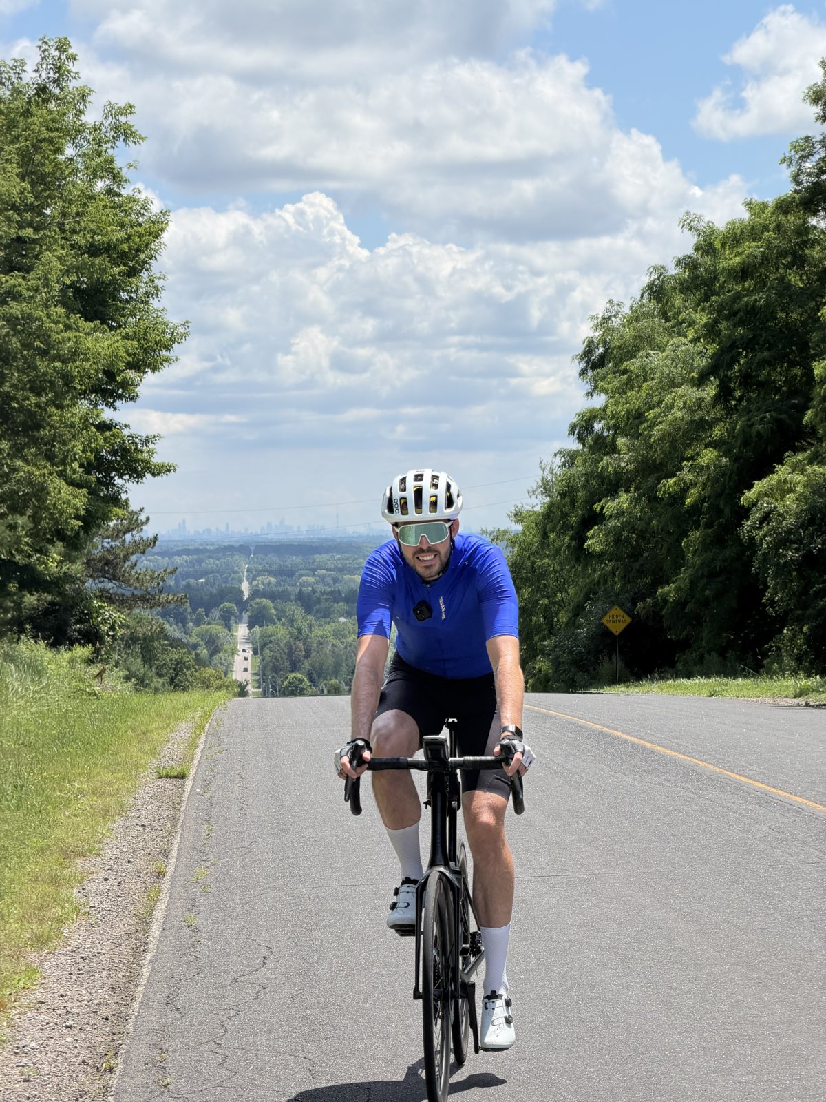Francis riding toward the camera on Mount Pleasant with the distant Toronto skyline behind