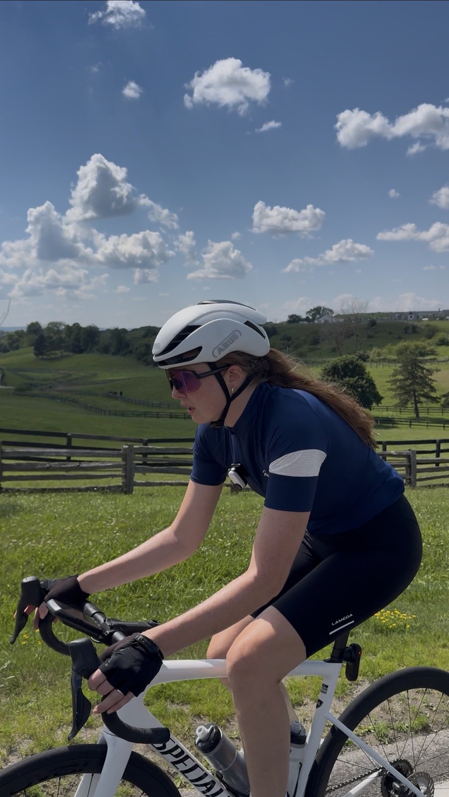 Bailey riding past a rail fence and rolling green Caledon farmland under a big blue sky