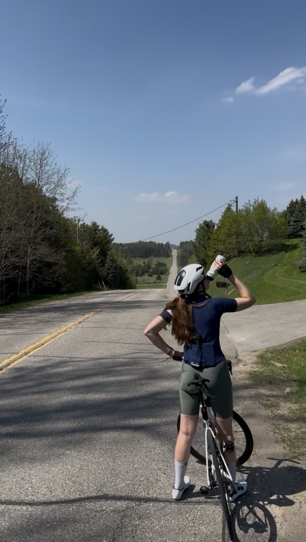 Rider pausing at the roadside above a long rolling descent