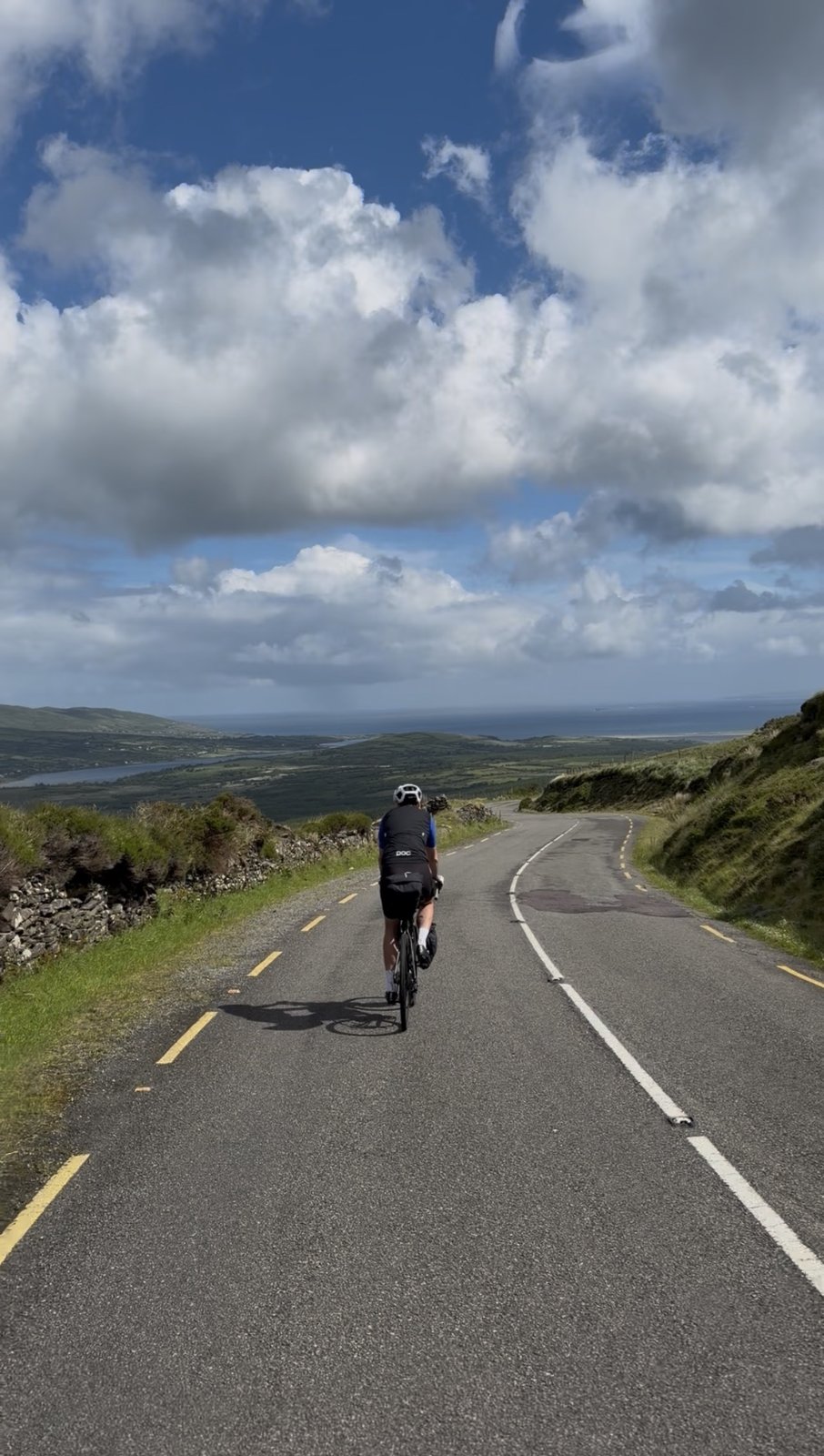 A rider on the open descent with the valley and distant lakes opening out beneath a big sky
