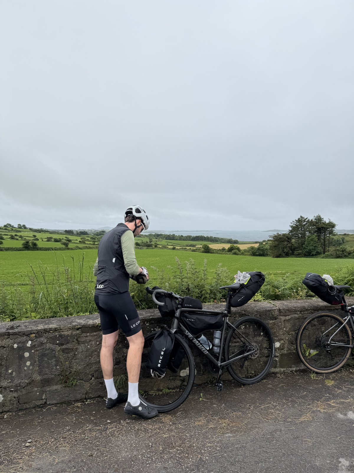 Francis stopped at his loaded bike on a stone bridge over green West Cork fields with the sea in the distance