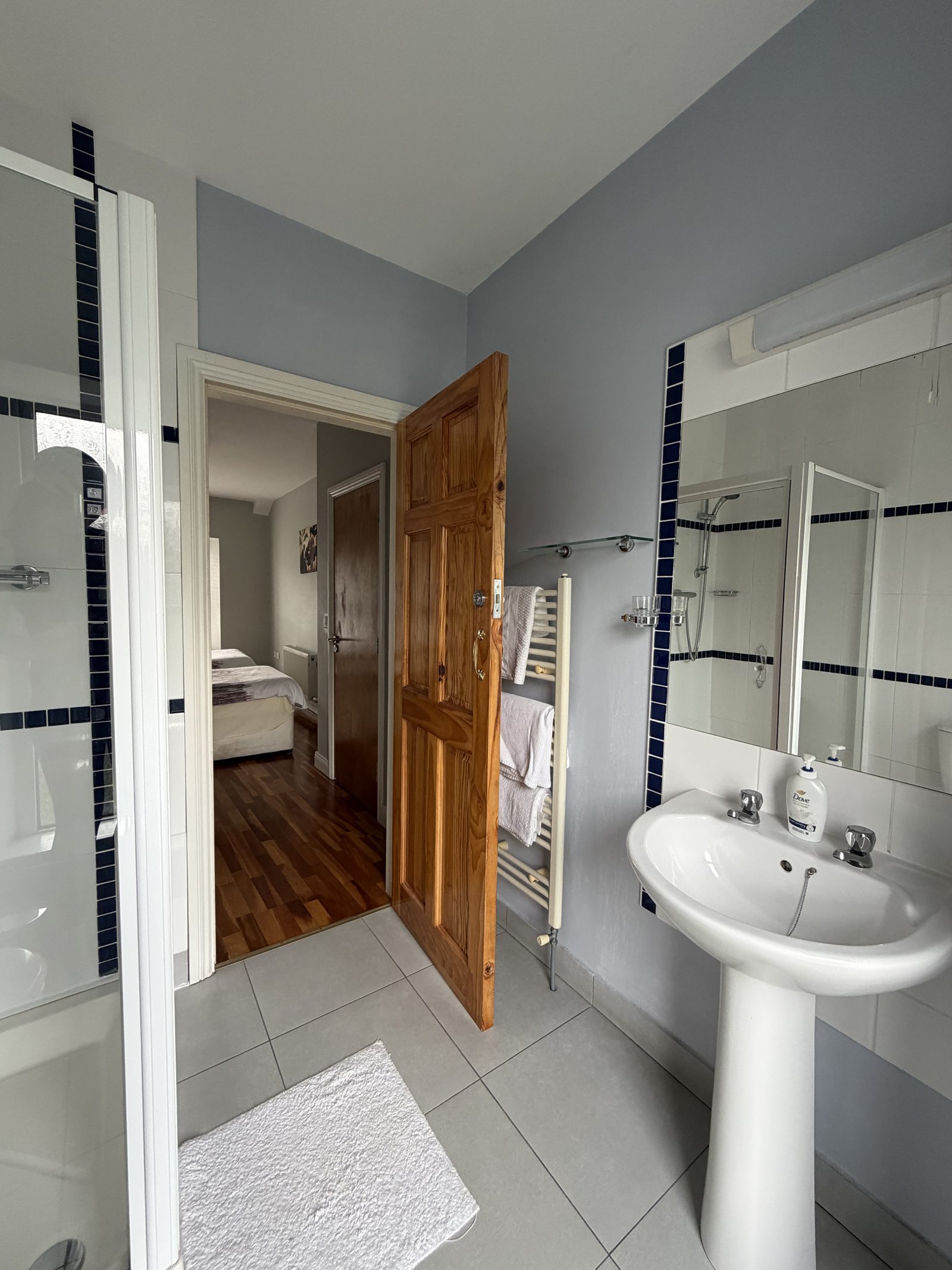The bright tiled en-suite bathroom with a walk-in shower and pedestal sink