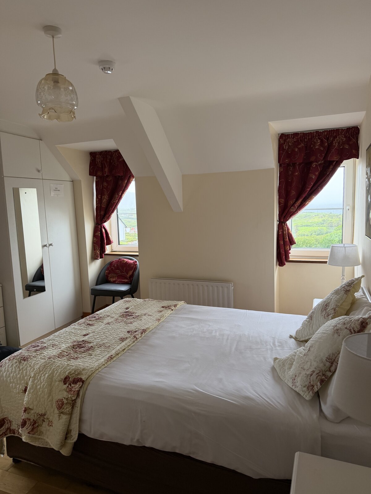 A bright bedroom at Coulagh Bay House with a sea view through the window and a floral bed runner