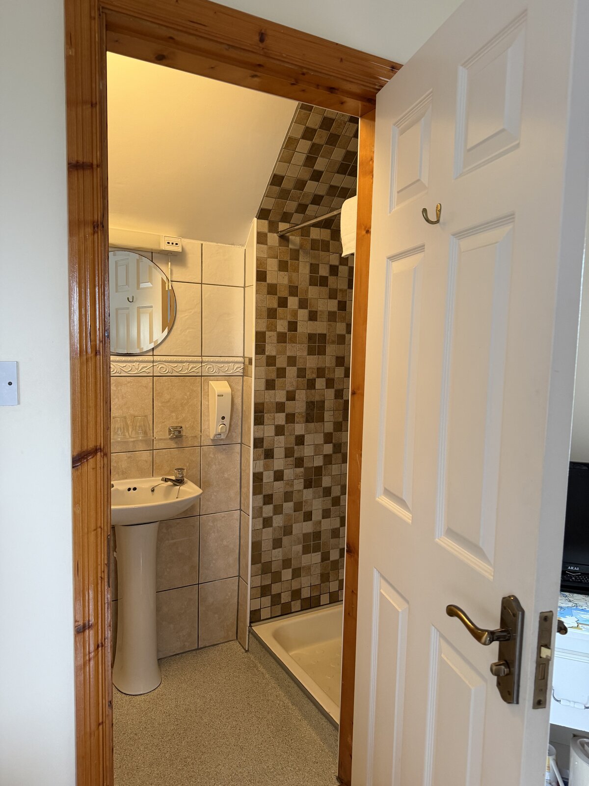 The tiled en-suite bathroom with a walk-in shower and pedestal sink