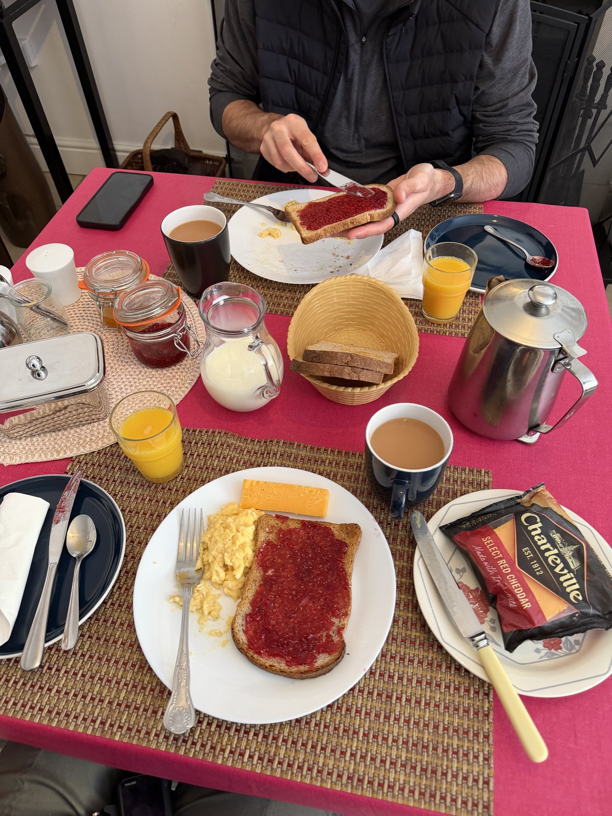 A homemade breakfast spread at Síve Hostel: toast and jam, cheese, tea and orange juice on a pink tablecloth