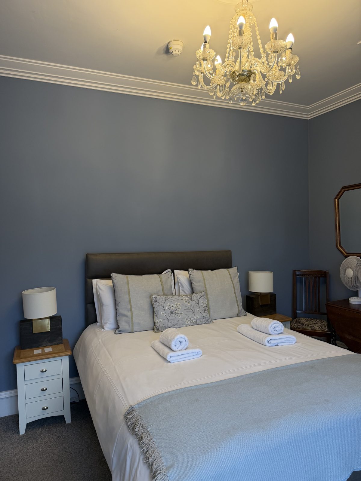 A double bedroom at Áras de Staic with a chandelier, antique side tables and fresh towels on the bed