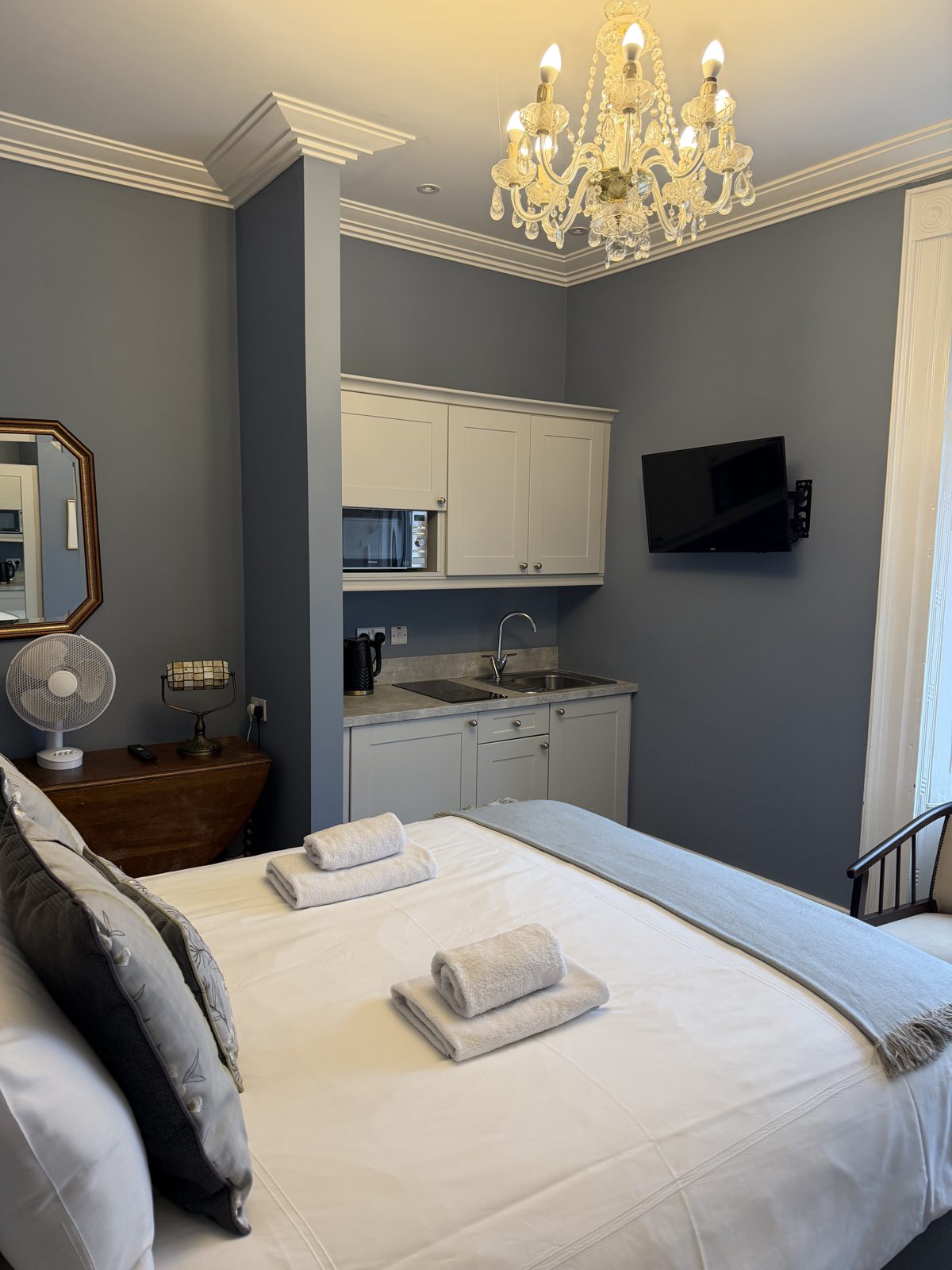 A studio suite at Áras de Staic with a double bed and a compact kitchenette against a grey feature wall