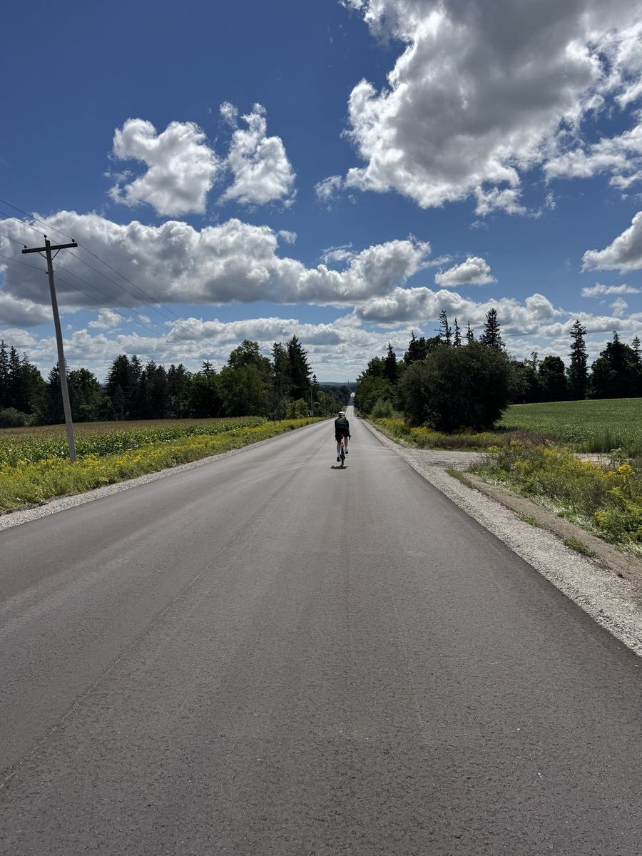 A rider small in the distance on a straight open farm road near Loretto